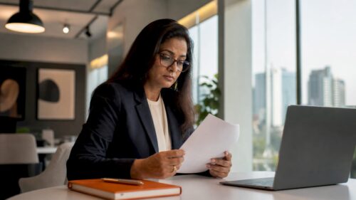 Woman reviewing financial compliance documents at desk